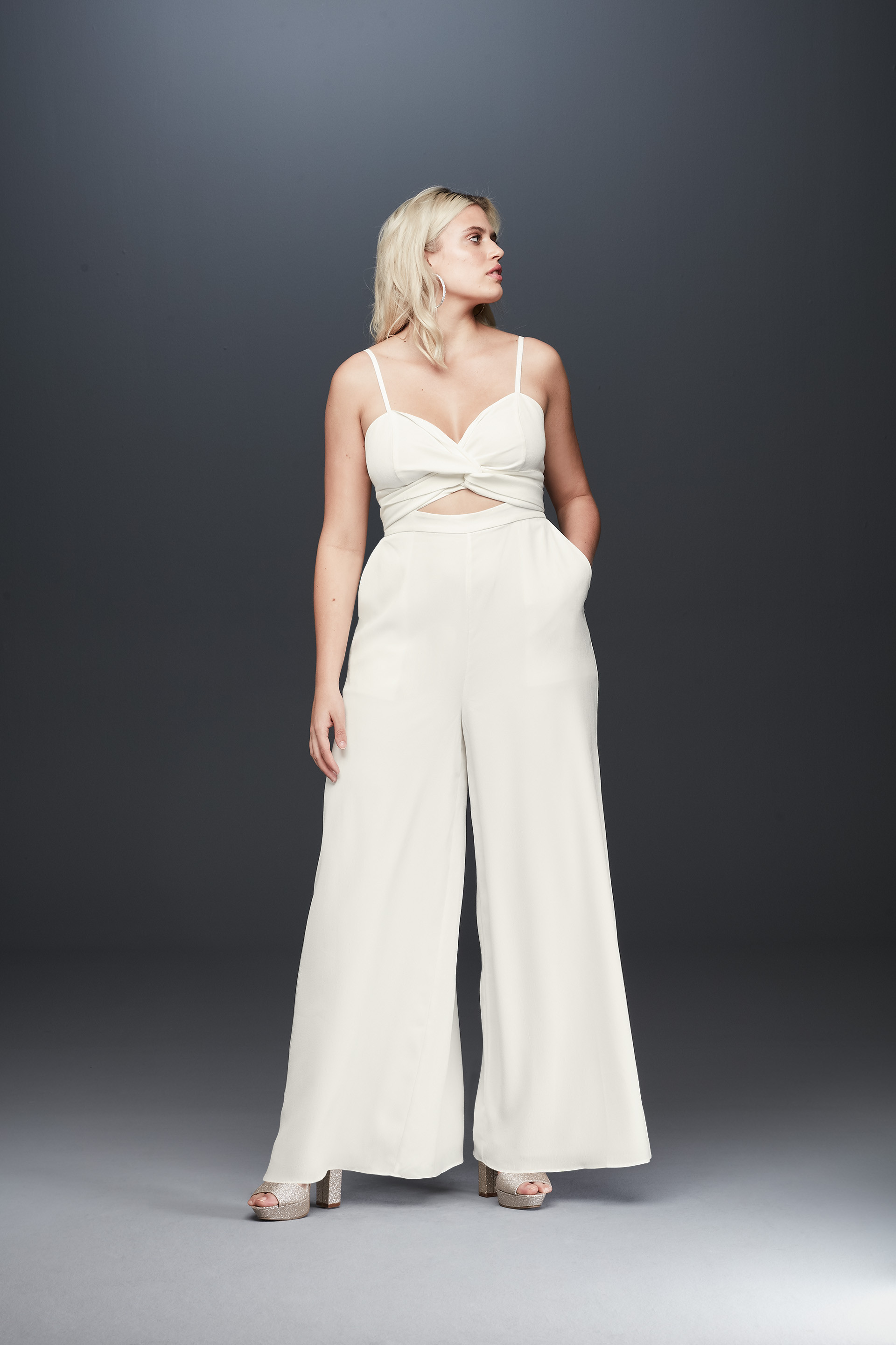 Bride looking away in spaghetti strap bridal jumpsuit, Fame and Partners x David's Bridal collection