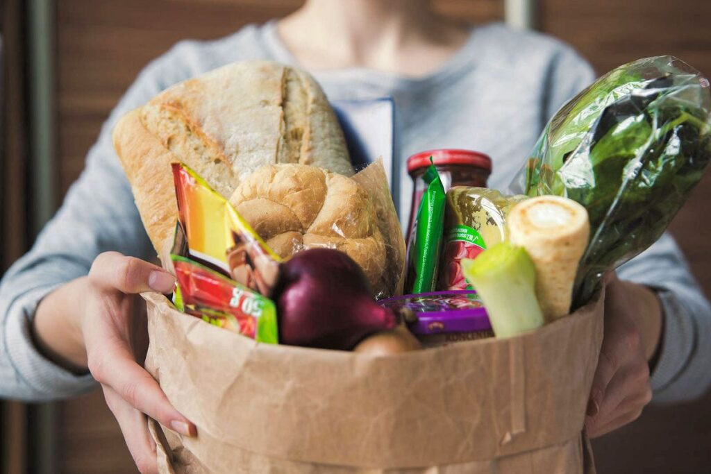 alt text: Volunteers delivering groceries to a senior's home.