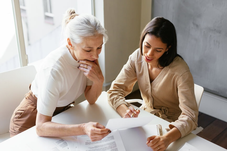 Two business women at a desk looking over paperwork to find out how to lower their taxable income, highlighting the importance of strategic financial planning for businesses