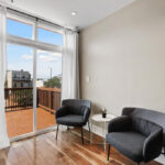 A cozy seating area in DC with two black chairs next to a large window, providing ample natural light and a view of the city.