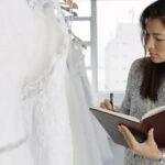 Woman looking at notebook in wedding dress shop