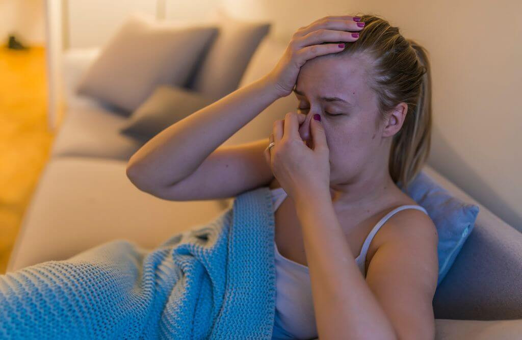 A woman experiencing sinus headaches, a potential sign of wisdom teeth issues