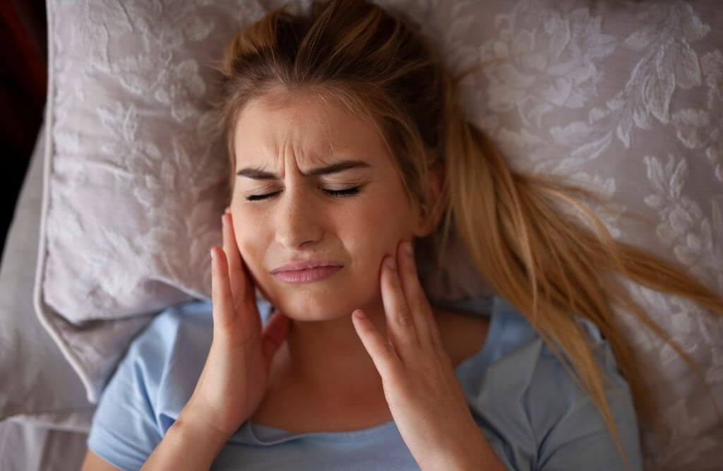 A woman experiencing pain in both jaws, potentially linked to wisdom teeth issues