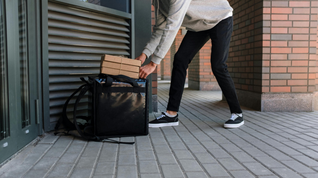 A person putting food deliveries in a delivery bag.