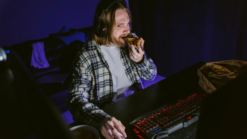 A man eating pizza while live-streaming.