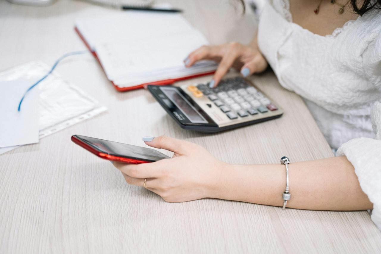 Young woman using a calculator and smartphone while analyzing finances