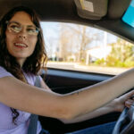 A person filling out a mileage log while sitting in a car.