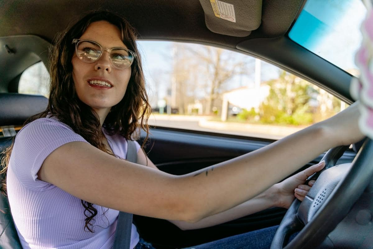 A person filling out a mileage log while sitting in a car.