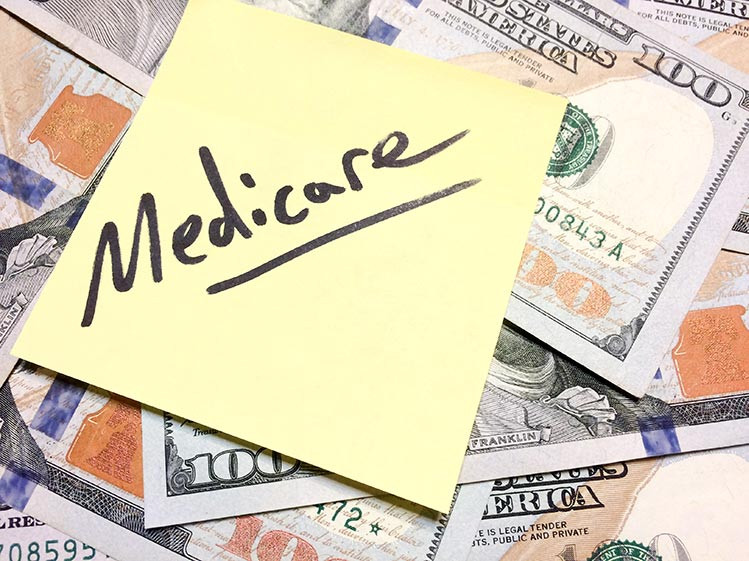 Senior woman with a healthcare professional discussing Medicare plans medicare-and-cash-IS-1202330455