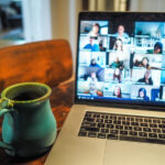 Young woman smiling as she works at her computer with a cup of coffee