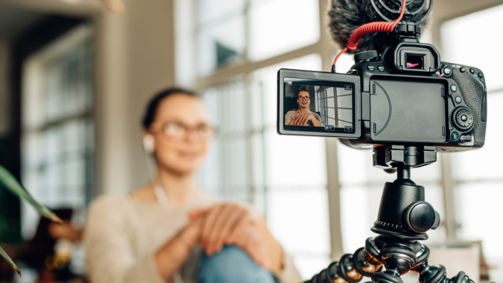 A woman is sitting in front of a video camera, getting ready to record or participate in a video call.