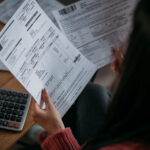 Close-up of female hands with pay slips, utility bills, account statements, payment receipts. A woman makes a count of household, family expenses