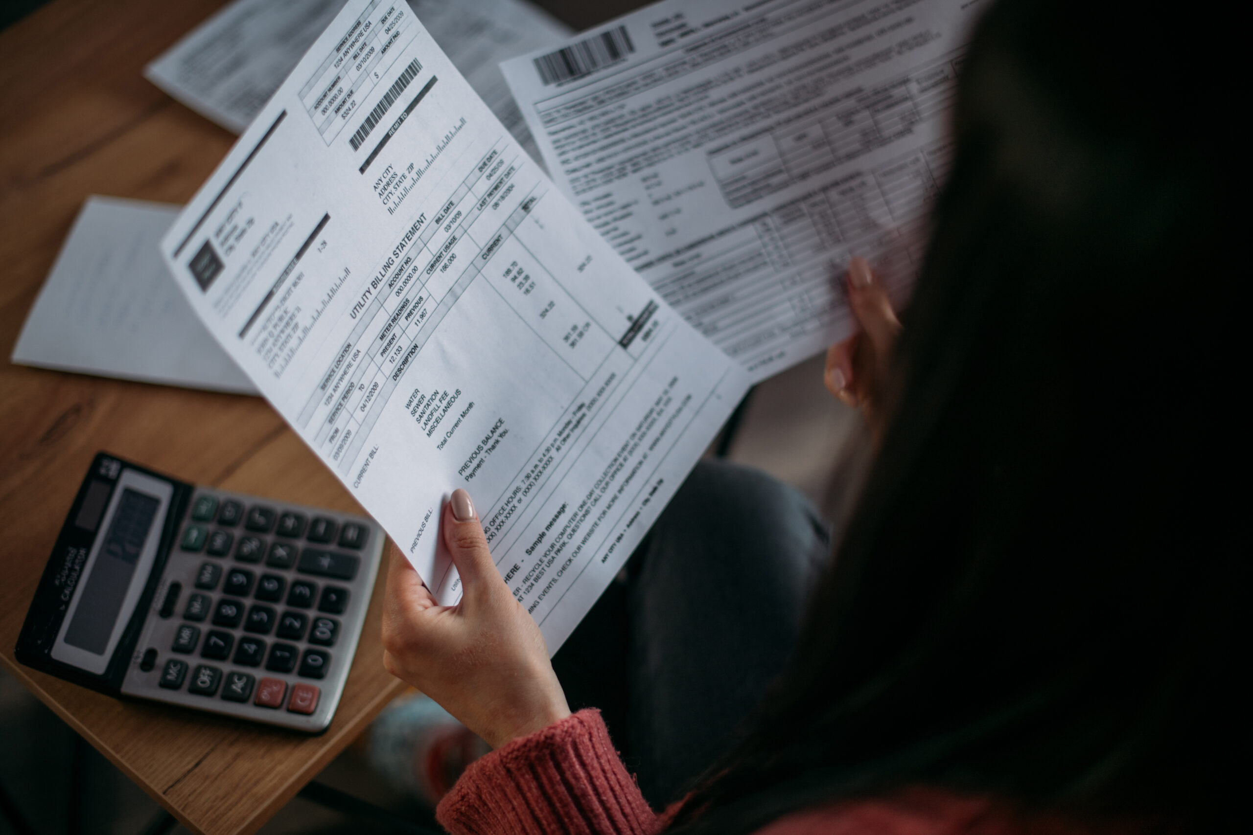 Close-up of female hands with pay slips, utility bills, account statements, payment receipts. A woman makes a count of household, family expenses