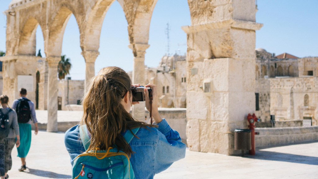 A woman taking a picture of a historic sight using a DSLR camera.