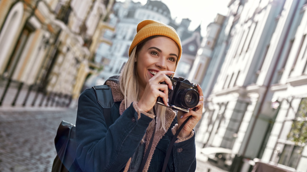 A woman is using her camera to take a photograph, concentrating on how to make 0 a day with photography.