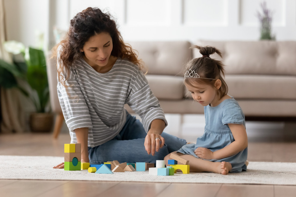 A babysitter playing with blocks with a child, highlighting the daily work that leads to reportable income.