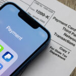 Payment apps like PayPal and Venmo are seen on an iPhone on top of Form 1099-k, displaying the modern methods of income reporting through third-party processors.