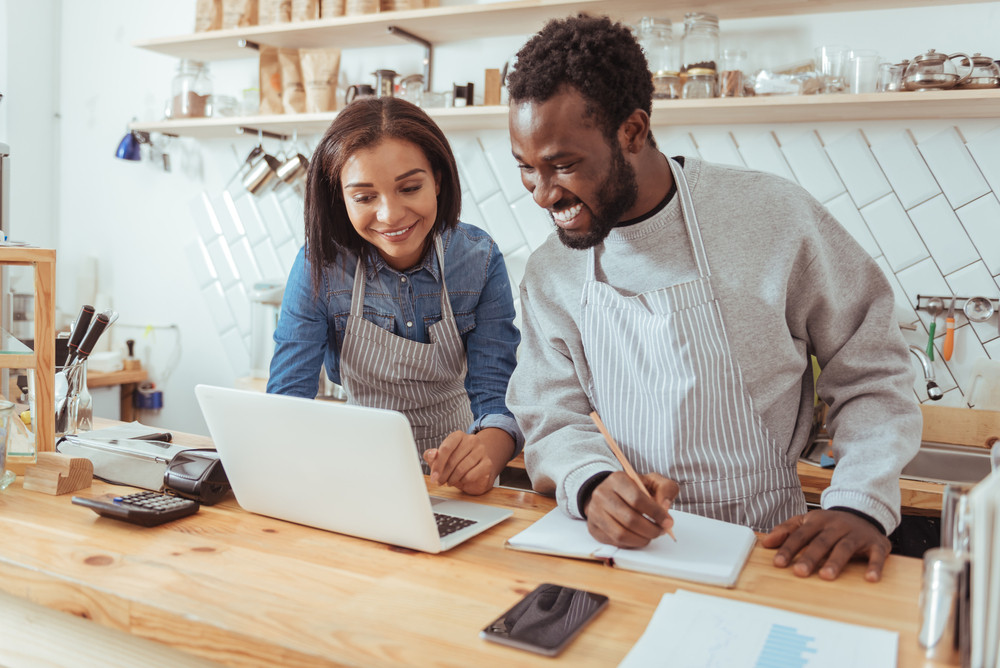 Pleasant young baristas browsing the web and running their own business from a home office, illustrating the possibilities for business expense deductions.
