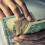 Close-up of someone counting cash, symbolizing the need to report all babysitting income.
