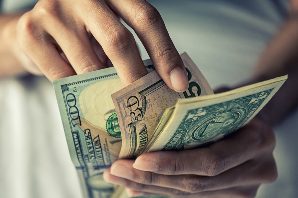Close-up of someone counting cash, symbolizing the need to report all babysitting income.