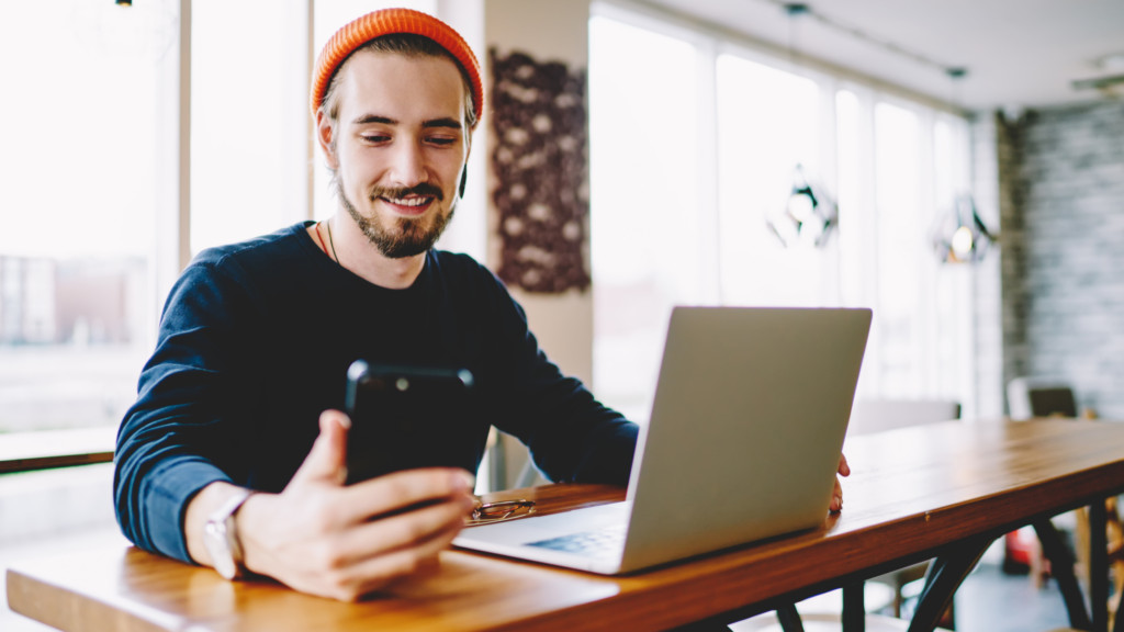 A person at a table is using a laptop and a phone for affiliate marketing tasks, emphasizing focus and productivity.