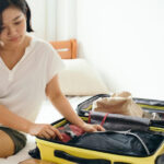 Woman packing her suitcase on a bed