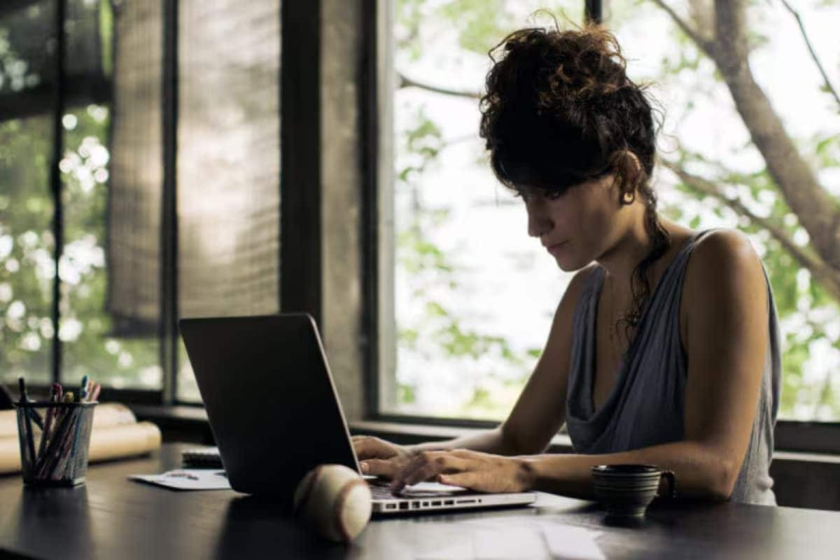 Person calculating taxes with a calculator, tax form, and laptop