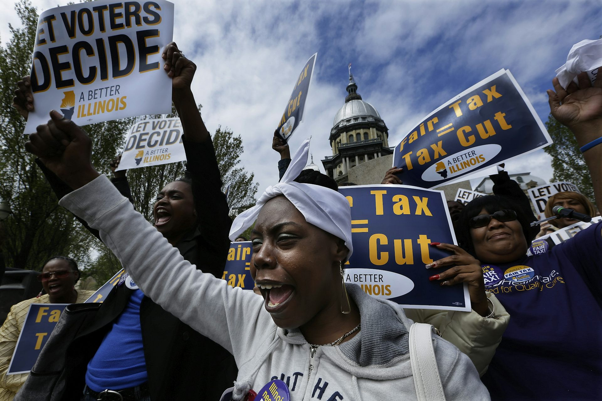 People outside the Illinois Capitol wave signs calling for a vote on the state
