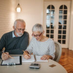 An older couple looking at documents at their kitchen table