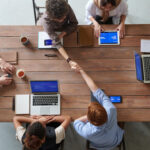People shaking hands as a business deal (partnership) on a glass office table