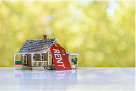 A toy house and a calculator on a table, symbolizing the calculation of rental income and its potential effect on SSI benefits.